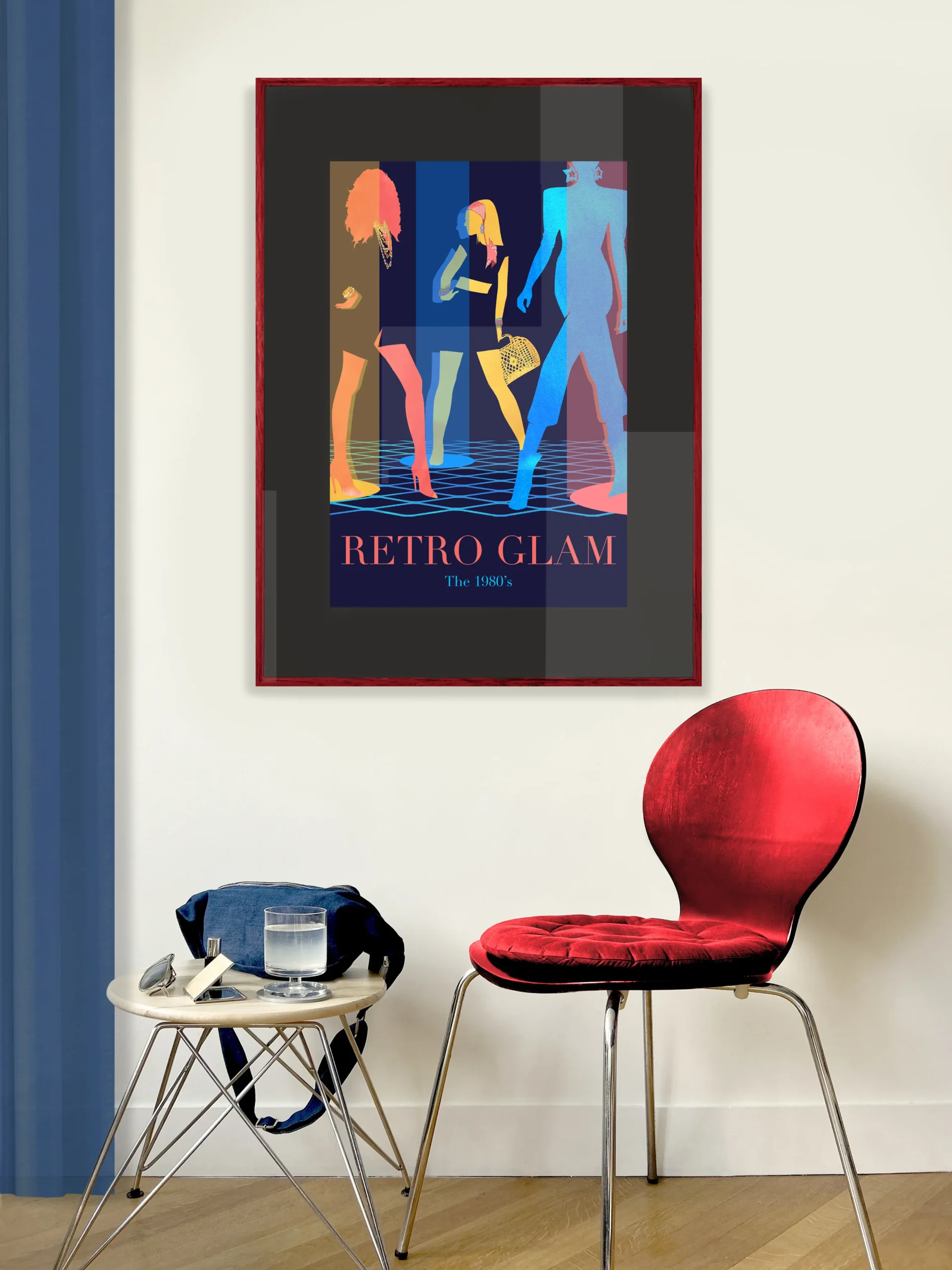 Red frame with a poster showing three colored silhouettes, red, yellow and blue, of women dressed in 1980's outfits, golden big jewelry, scarves, high heels, miniskirts and big hair. Beams in yellow, blue and red are coming down from the ceiling. On the floor is a light blue grid. The text "Retro Glam" is featured at the bottom. To the left of the poster is a blue curtain and on the floor stands a small round table with a glass, pocket mirror, sunglasses and a blue denim bag. Next to the table is a red chair.